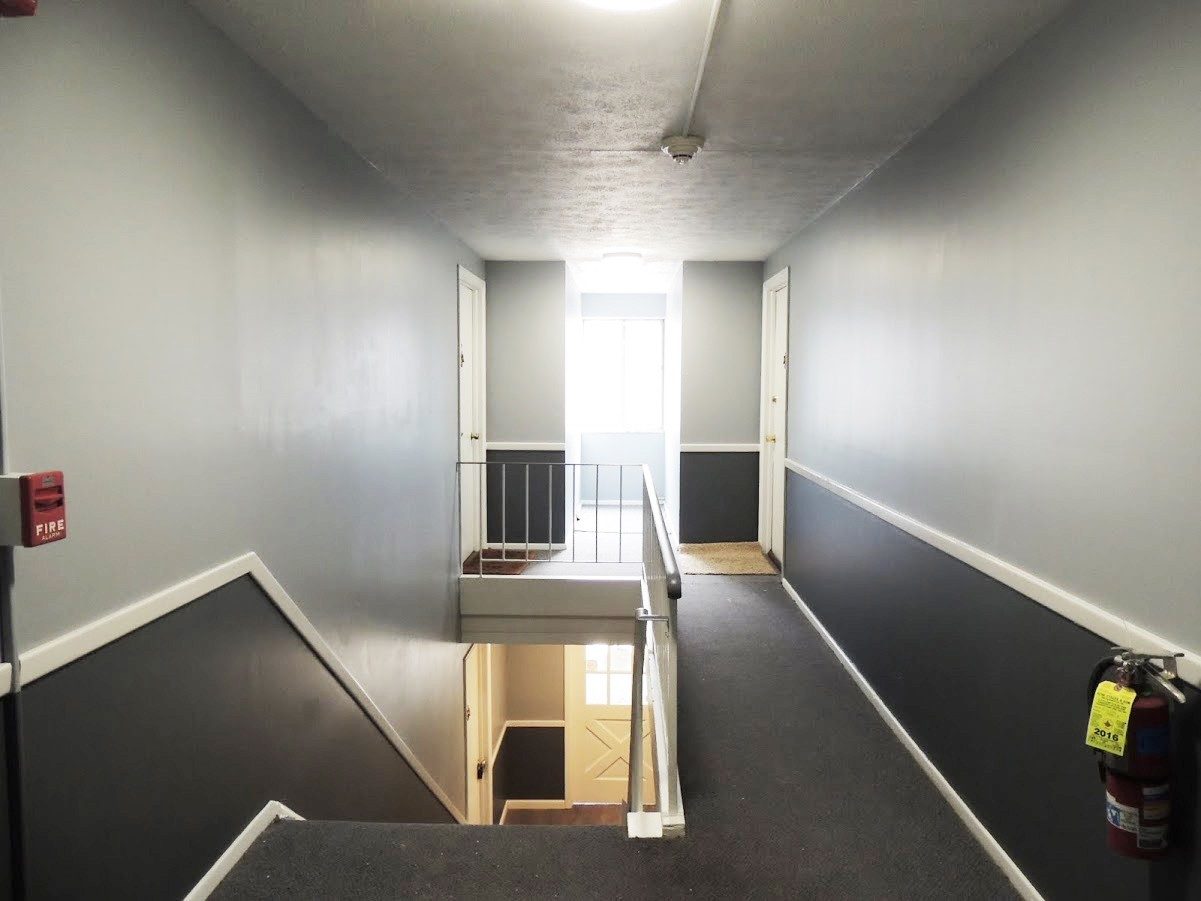 An apartment building stairwell mid-renovation with fresh paint and new treads.